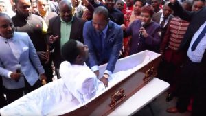 A man touching a man in coffin