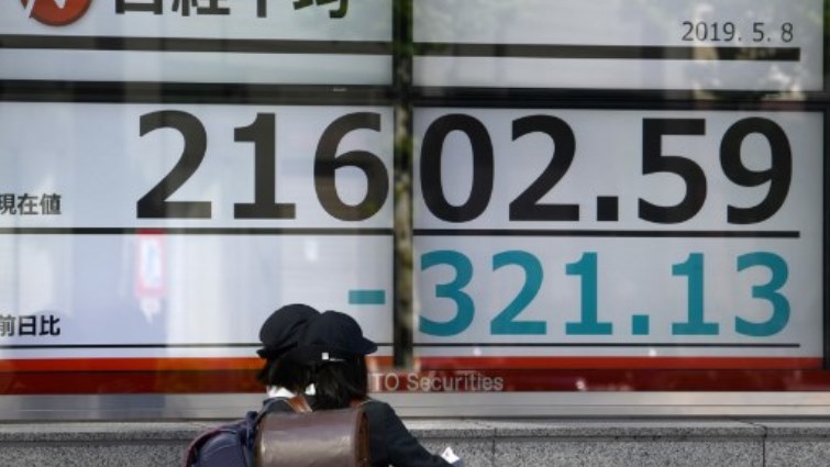 Elementary schoolchildren walk past an electronics stock indicator in the window of a securities company in Tokyo displaying the closing numbers for the Tokyo Stock Exchange.