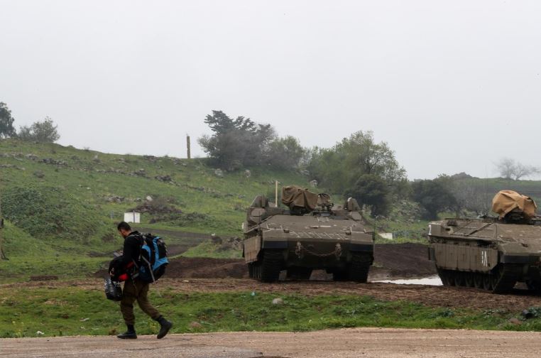 An Israeli soldier walks past armoured Israeli military vehicles in the Israeli-occupied Golan Heights.