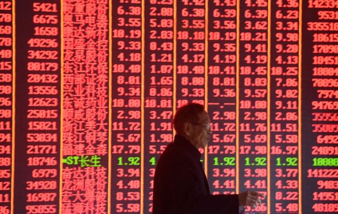 A man walks past a share index board