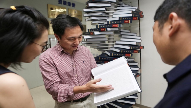 Scientist He Jiankui shows "The Human Genome", a book he edited, at his company Direct Genomics in Shenzhen,