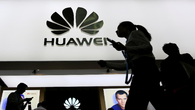 A person walking and holding a Huawei handset