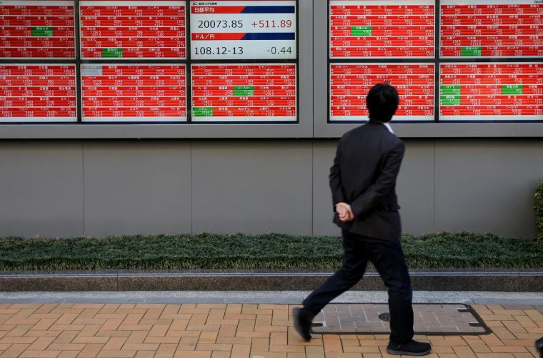 A man looks at an electronic board showing the Nikkei stock index outside a brokerage in Tokyo.