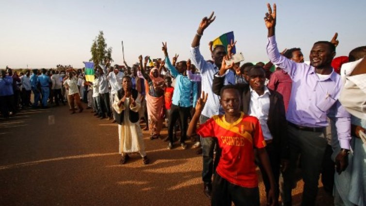 Sudanese people flash the victory gesture as they gather outside al-Huda prison in the capital Khartoum's twin city of Omdurman.
