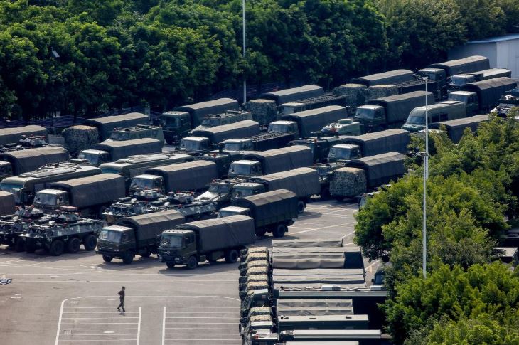 Service men walk past military vehicles in the parking area of the Shenzhen Bay Sports Center in Shenzhen across the bay from Hong Kong.
