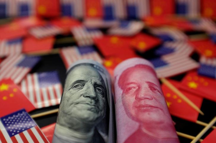A U.S. dollar banknote featuring American founding father Benjamin Franklin and a China's yuan banknote featuring late Chinese chairman Mao Zedong are seen among U.S. and Chinese flags in this illustration.