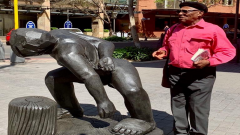 Pitika Ntuli standing next to his sculpture