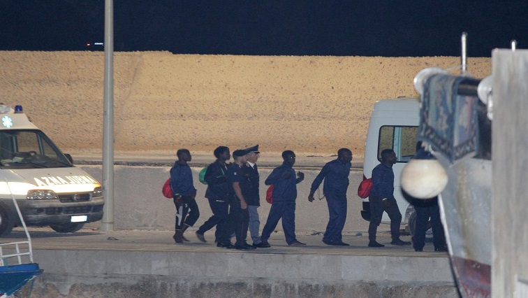 Migrants board a vehicle at the port.