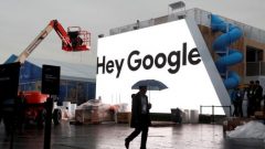 A man walks through light rain in front of the Hey Google booth under construction at the Las Vegas Convention Center in preparation for the 2018 CES in Las Vegas.