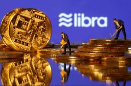 Small toy figures are seen on representations of virtual currency in front of the Libra logo in this illustration picture.