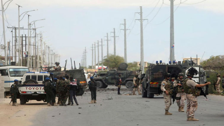 Italian and Somali security forces are seen near armoured vehicles at the scene of an attack on an Italian military convoy in Mogadishu, Somalia.