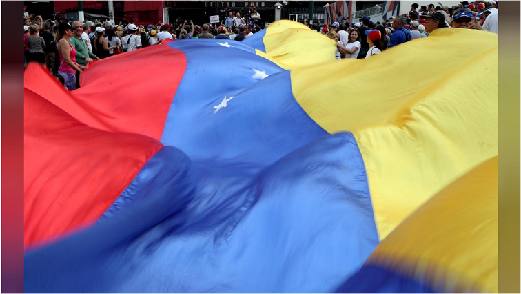 People display a huge Venezuelan flag as they take part in a protest against Venezuelan President Nicolas Maduro's government in Caracas, Venezuela