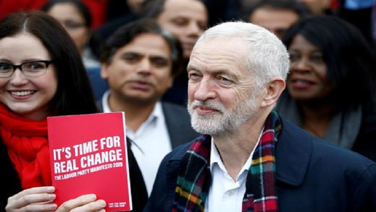Britain's opposition Labour Party leader Jeremy Corbyn poses with his party's manifesto as he visits Labour activists.