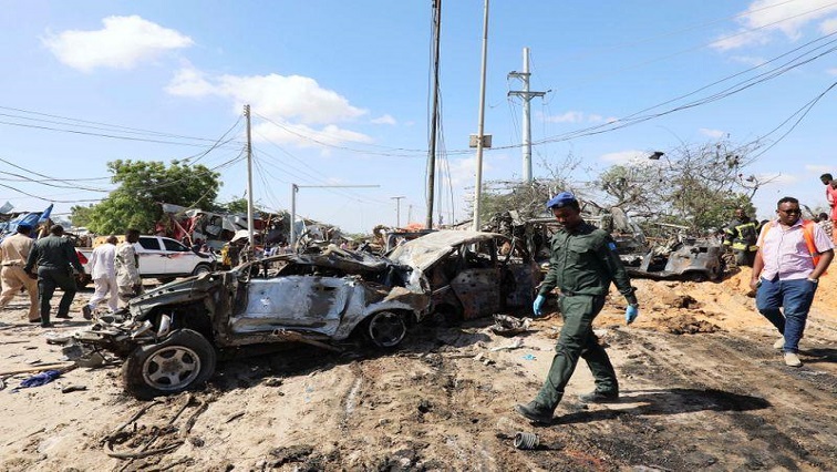 A Somali police officer walks past a wreckage at the scene of a car bomb explosion at a checkpoint in Mogadishu.