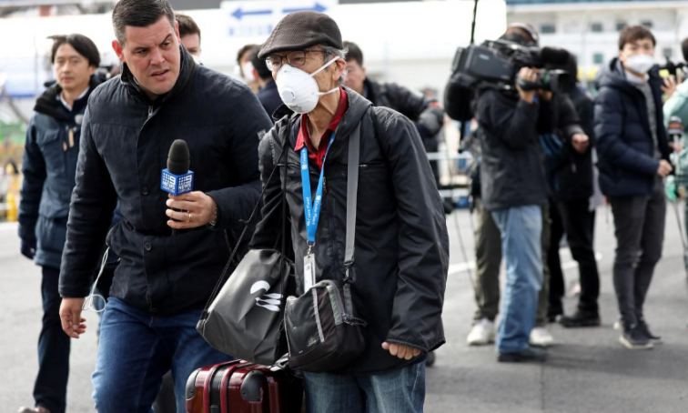 A member of the media approaches a passenger after he walked out from the cruise ship Diamond Princess at Daikoku Pier Cruise Terminal in Yokohama, south of Tokyo.