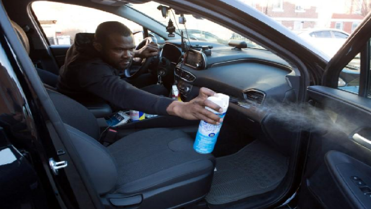 Uber and Lyft driver Adama Fofana sprays disinfectant in his car in New York City.