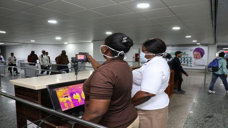 Officials monitor thermal scanners as passengers walk past upon arrival of a flight into Lagos, Nigeria January 22, 2020.