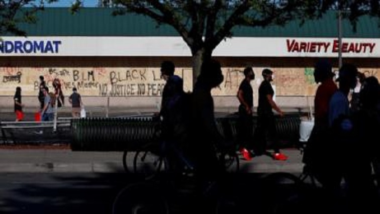People walk past boarded up stores as demonstrations against the death in Minneapolis police custody of George Floyd continue, in Minneapolis, Minnesota, U.S.