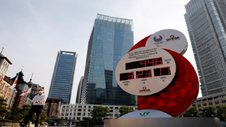 A man wearing a protective mask walks past a countdown clock for the Tokyo 2020 Olympic Games amid the coronavirus disease (COVID-19) outbreak in Tokyo.