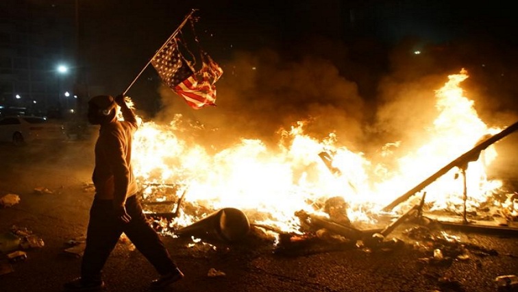A protestor holds a burnt American flag during a protest against the death in Minneapolis police custody of African-American man George Floyd, in St Louis, Missouri, U.S., June 1, 2020.