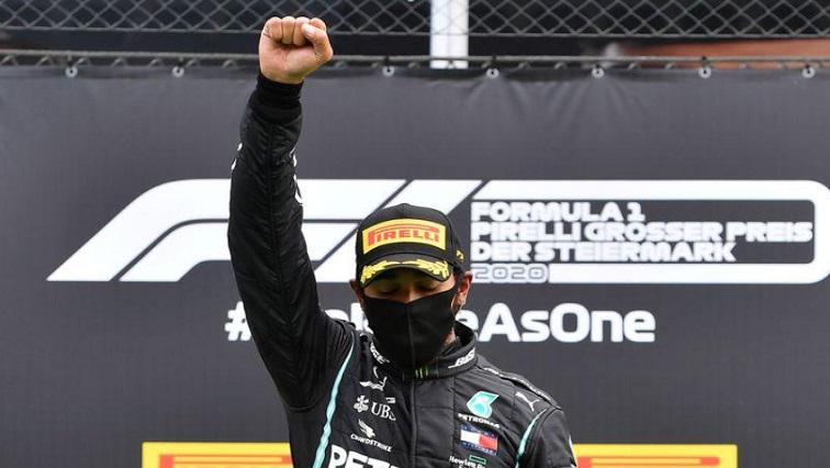 Mercedes' Lewis Hamilton wears a protective face mask as he celebrates winning the race on the podium with the trophy, following the resumption of F1 after the outbreak of the coronavirus disease (COVID-19)