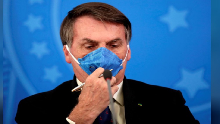 Brazil's President Jair Bolsonaro adjusts his protective face mask at a press statement.