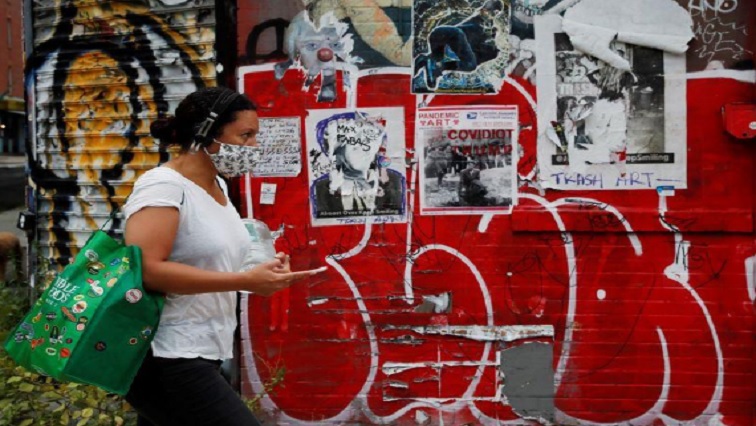 A woman wearing a protective face mask walks past graffiti amid the spread of the coronavirus disease (COVID-19) in the Brooklyn borough of New York, U.S., August 4, 2020.