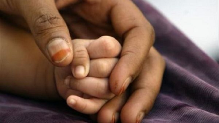A mother holds her baby's hand