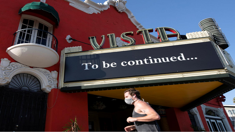 A person wearing a face mask jogs by the Vista theatre during the outbreak of the coronavirus disease (COVID-19), in Los Angeles, California, US.