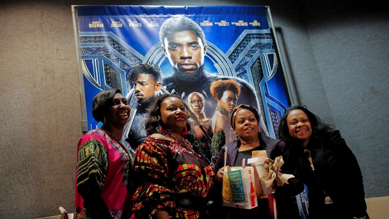 A group of women pose for a photo in front of a poster advertising the film "Black Panther" on its opening night of screenings in Manhattan, New York, U.S., February 15, 2018.
