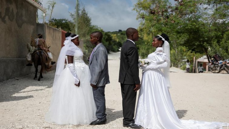 Patricia, who is pregnant, and Obelson, who got married in a joint ceremony with another pregnant couple who they did not know, to share the costs of the ceremony, pose for a photo outside the church where they got married in Baie de Henne, Nord Ouest Department, Haiti, on October 27, 2018.