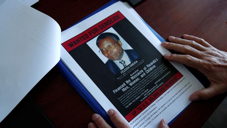 Eric Emeraux, head of the Gendarmerie's Central Office for Combating Crimes Against Humanity, Genocides and War Crimes (OCLCH), diplays documents with a wanted poster depicting a photograph of Felicien Kabuga during an interview with Reuters at his office, about the arrest of Rwandan genocide fugitive suspect Felicien Kabuga, in Paris, France, May 19, 2020.