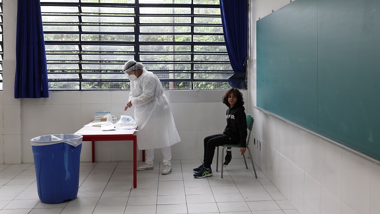 A healthcare worker prepares to perform a PCR test on student Theo Barbosa Rodrigues at Almir Pereira Bahia Reverendo state school in Taboao da Serra, on the outskirts of Sao Paulo.