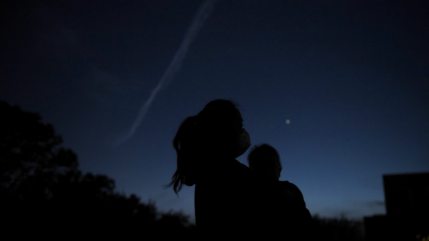 Thao Galvan holds her son Nathan while they view Jupiter and Saturn during a planetary conjuction, as they appear close together in a rare celestial event in Houston, Texas, U.S., December 21, 2020.