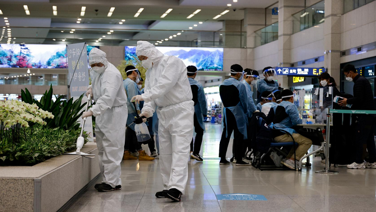 Workers wearing protective gear disinfect an arrival gate as other workers check passengers from overseas upon their arrival at the Incheon International Airport, amid the COVID-19 pandemic in Incheon, South Korea.