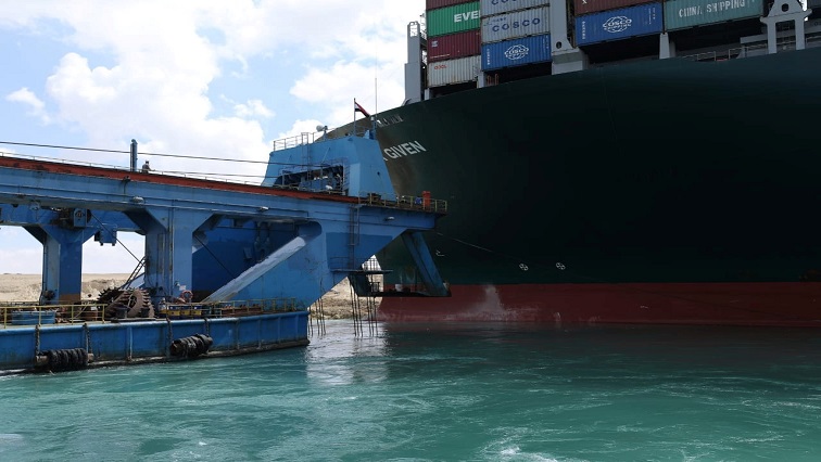 A dredger attempts to free stranded container ship Ever Given, one of the world's largest container ships, after it ran aground, in Suez Canal, Egypt.
