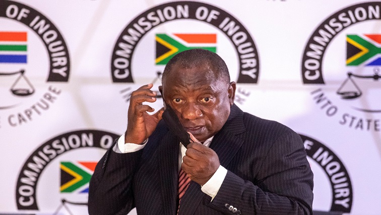 Ramaphosa adjusts his mask as he appears to testify before the Zondo Commission of Inquiry into State Capture in Johannesburg.