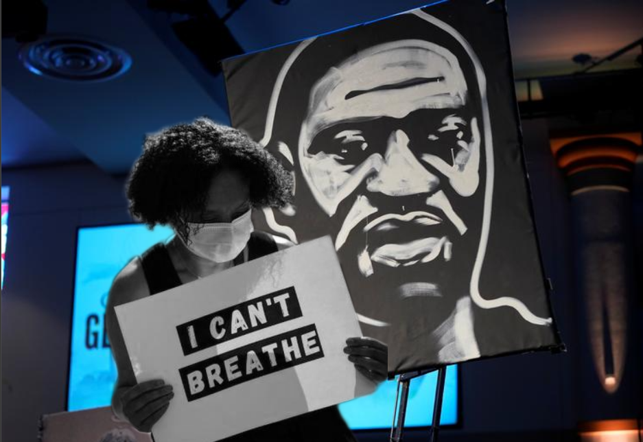 A protestor holds up a 'I can't breathe' poster in front of another poster of George Floyd following his killing
