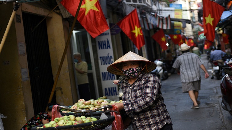 FILE PHOTO: A vendor walks in an alley decorated with national flags ahead of the upcoming elections in Hanoi, Vietnam, May 19, 2021. Picture taken May 19, 2021.