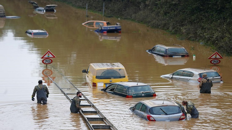 Members of the Bundeswehr forces, surrounded by partially submerged cars, wade through the flood water following heavy rainfalls in Erftstadt-Blessem, Germany, July 17, 2021.