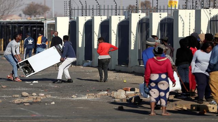 Looters carrying a refrigerator from a nearby shopping mall