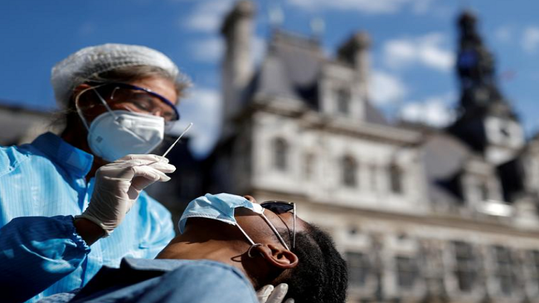 FILE PHOTO: A health worker, wearing a protective suit and a face mask, prepares to administer a nasal swab to a patient at a testing site for the coronavirus disease (COVID-19) installed in front of the city hall.