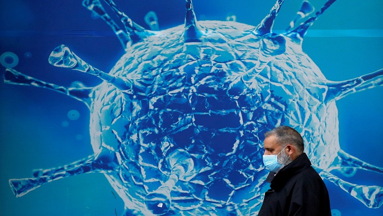 A man wearing a protective face mask walks past an illustration of a virus outside a regional science centre amid the coronavirus disease (COVID-19) outbreak. [File image]