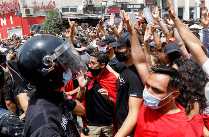 Demonstrators gather in front of police officers standing guard during an anti-government protest in Tunis, Tunisia, July 25, 2021