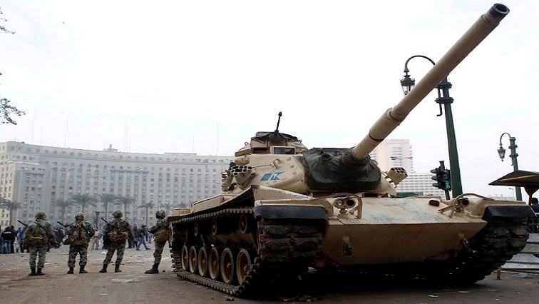 Egyptian army soldiers stand beside an armoured tank at Tahrir Square after wide-spread protests in downtown Cairo on January 29, 2011.