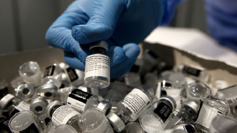 A nurse puts a used Pfizer-BioNTech COVID-19 vaccine vial in a disposal box with empty vials.