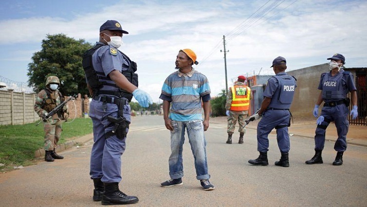 A member of the South African Police Service on patrol stops a men during a nationwide lockdown for 21 days to try to contain the coronavirus disease (COVID-19) outbreak, in Eldorado Park, South Africa, March 30, 2020.
