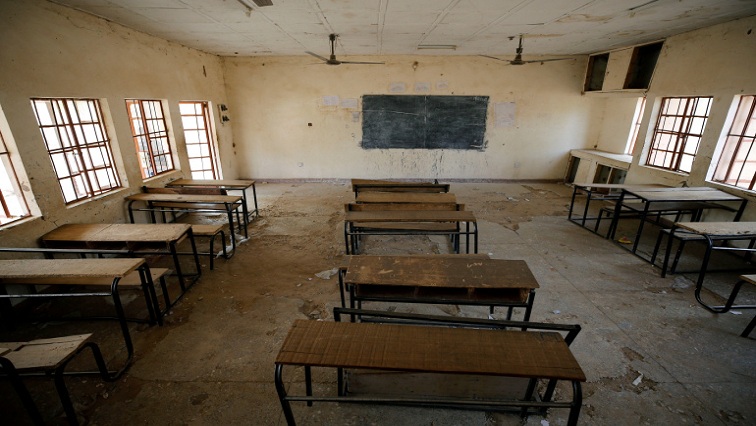 Empty classroom with an interactive board, desks and chairs.