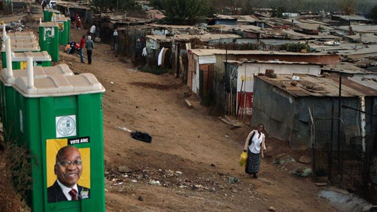 A woman walks past ANC-branded mobile toilets in an informal settlement.