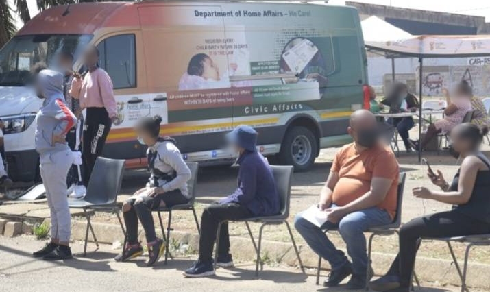 People sit in front of a Home Affairs mobile units based.